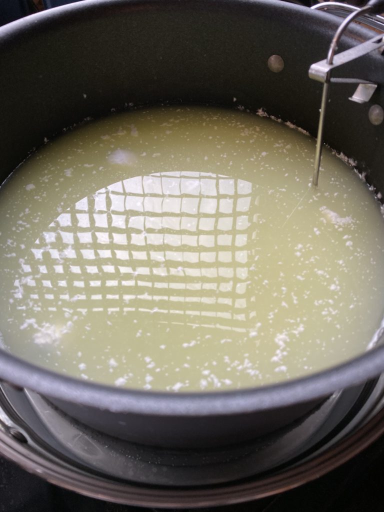 a pot with white-speckled liquid and a thermometer