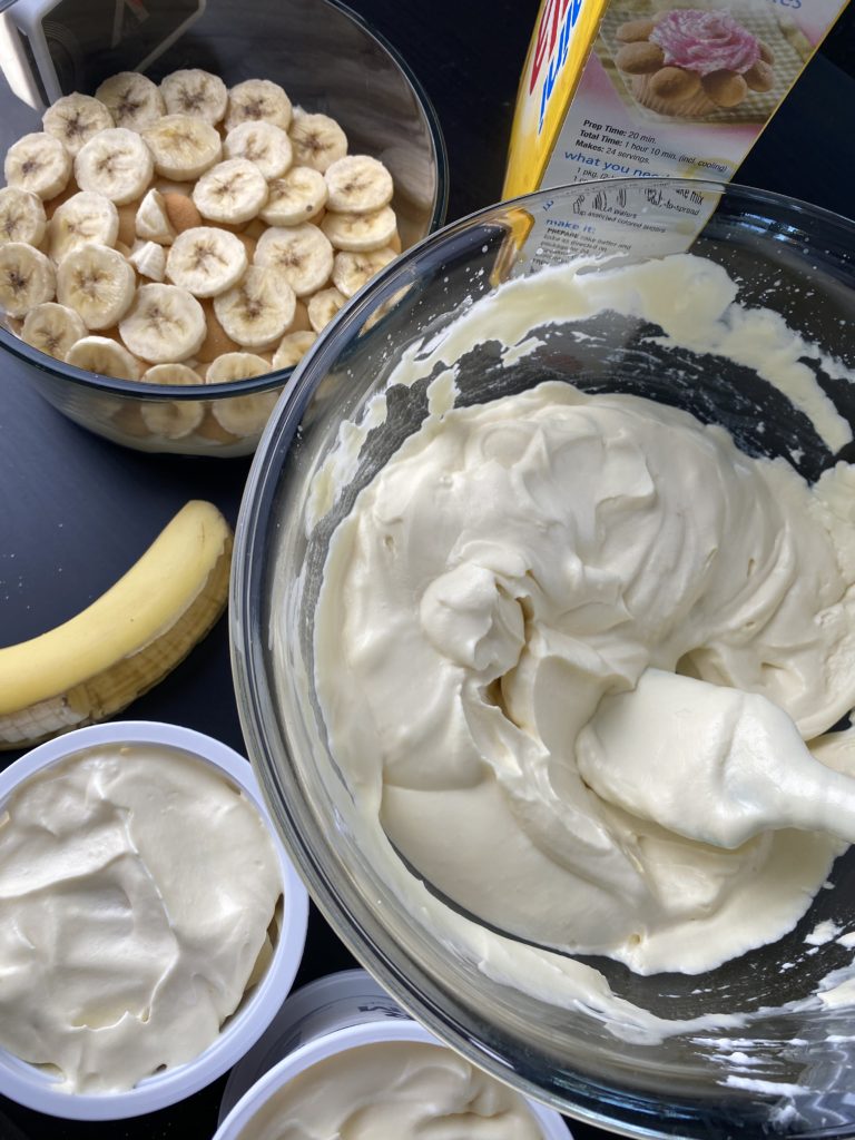 a bowl filled with nilla wafers and sliced bananas, and a larger bowl filled with pudding