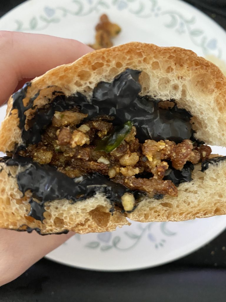 a sandwich using the french bread, with a black sauce and something fried for the filling